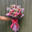 Hand holding a stargazer lily, red rose and thistle bouquet with purple snapdragons and gypsophila in purple marble wrap -- Blossom Surprise Northampton