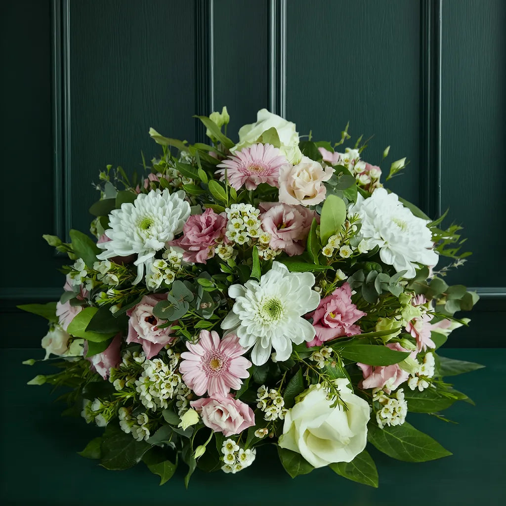 Sympathy Posy Bouquet of pink and white flowers with greenery against a dark green background Main image