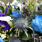 Bouquet of flowers with blue roses, purple iris, and greenery.
