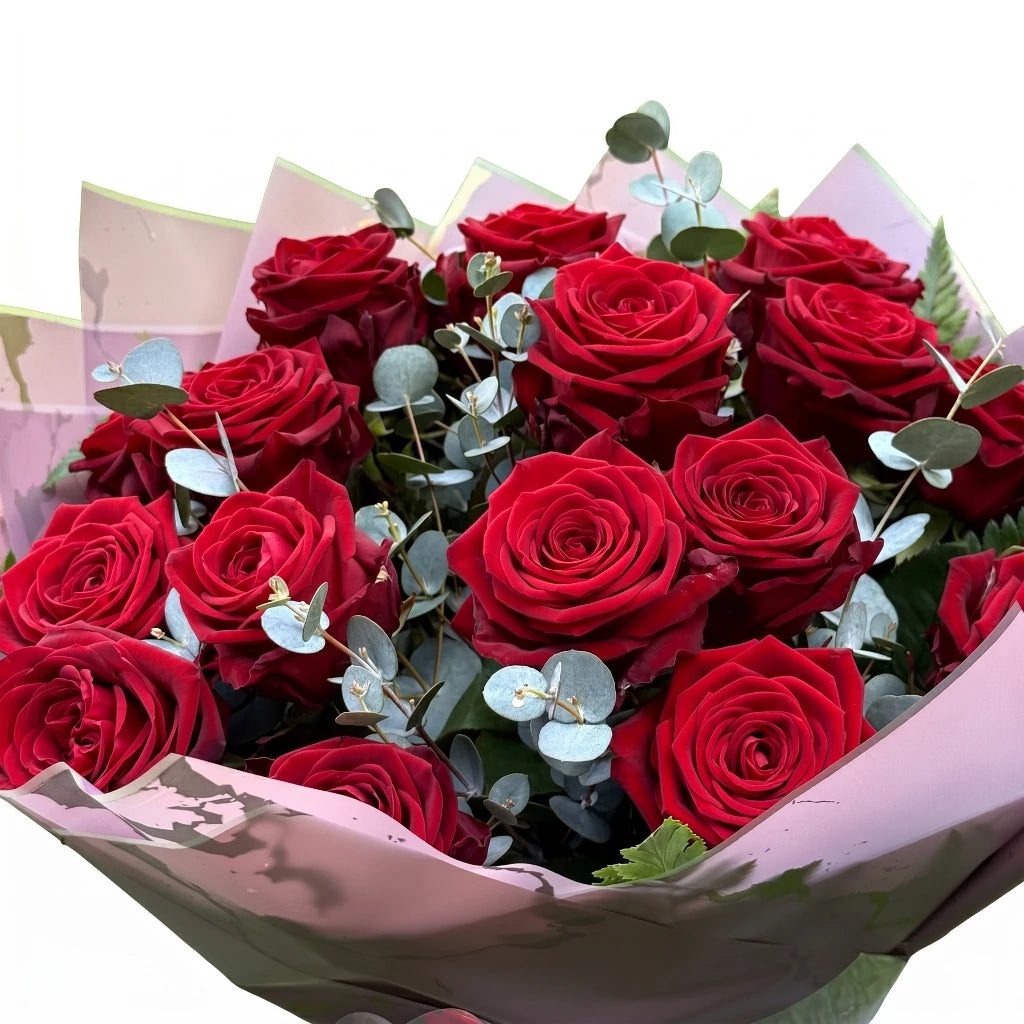 Bouquet of red roses with greenery in pink paper wrapping