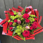Another overhead view of red rose and lime-green pompon chrysanthemum bouquet with opening pink lily buds, yellow solidago and fern in red and black luxury wrap - Blossom Surprise