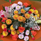 Overhead close-up of mixed flower bouquet with orange pompon chrysanthemums, coral roses, pink oriental lilies, soft pink daisies and white gypsophila in orange wrap -- Blossom Surprise