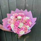 Hand holding a large bouquet of fifty blush, pink, cerise and white roses with pink carnations in a lilac paper wrap -- Blossom Surprise Northampton