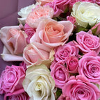A close-up bouquet of roses in shades of pink and cream, with several fully opened blooms and smaller buds nestled together.