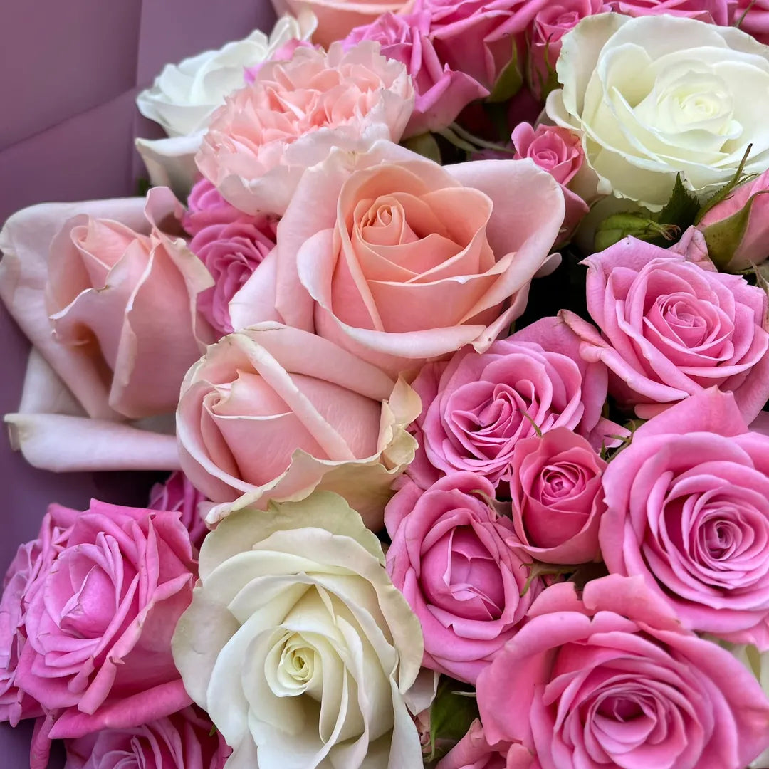 A close-up bouquet of roses in shades of pink and cream, with several fully opened blooms and smaller buds nestled together.