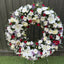Full open ring funeral wreath densely dressed with white lilies, red and cream roses, white chrysanthemums, statice and eucalyptus -- Blossom Surprise Northampton florist
