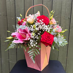 Red and cream rose, pink lily and lisianthus flower arrangement in a rose gold gift bag with carrying handle -- Blossom Surprise Northampton
