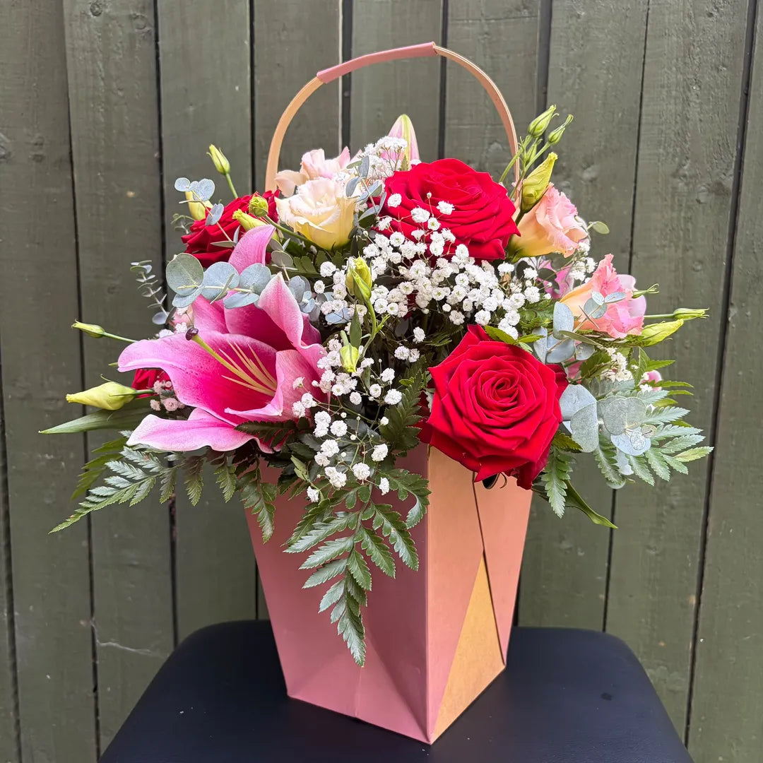 Red and cream rose, pink lily and lisianthus flower arrangement in a rose gold gift bag with carrying handle -- Blossom Surprise Northampton