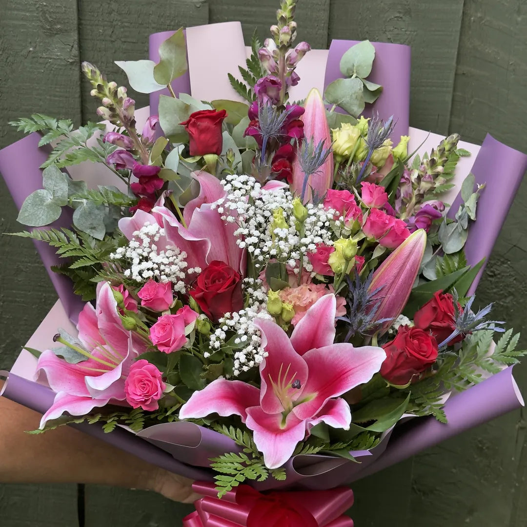 Stargazer lily bouquet with red and pink roses, snapdragons and silver-blue thistle in purple wrap -- Blossom Surprise Northampton