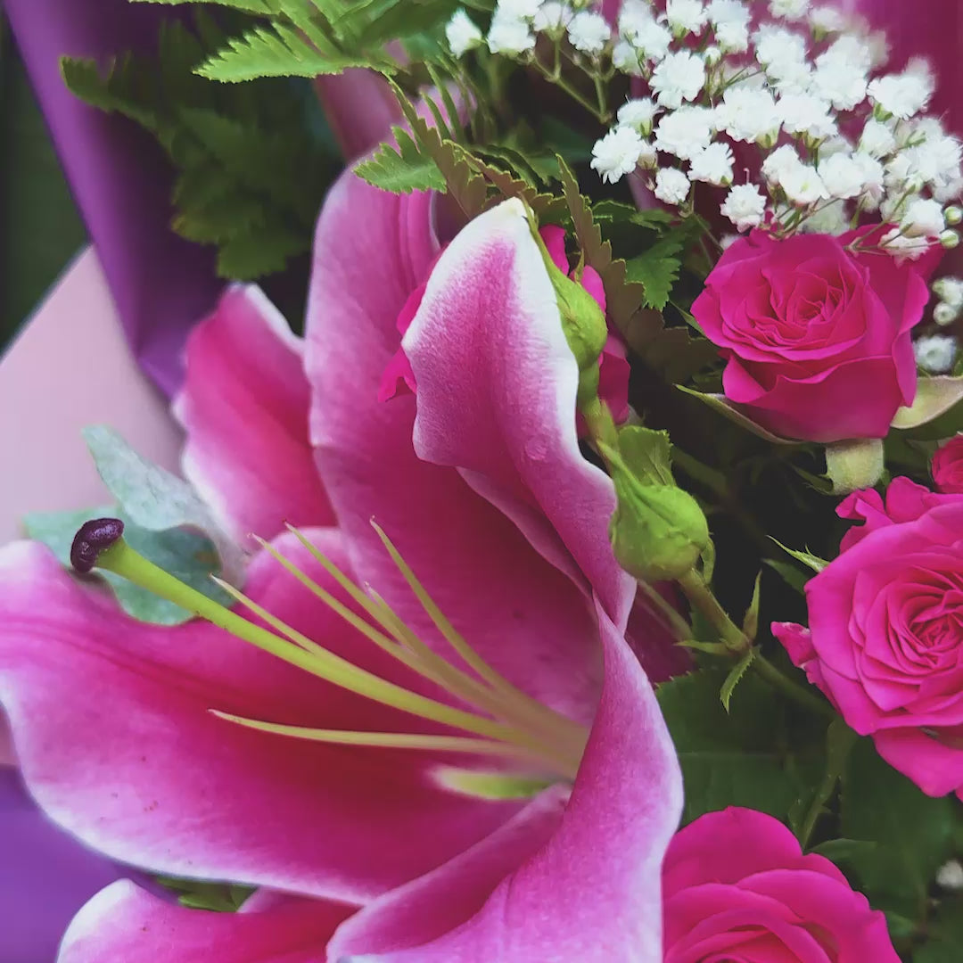 Stargazer lily and rose bouquet with magenta spray roses and eryngium thistle wrapped in purple paper with pink ribbon -- Blossom Surprise Northampton